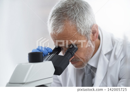 Mature man, microscope and scientist in lab for science innovation, vaccine or antiaging medicine. Life extension, medical or healthcare biologist looking at DNA chemistry in research or examination 142005725