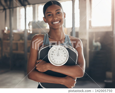 Scale, fitness and portrait of woman in gym for health, wellness and weightloss workout. Smile, training and female athlete with confidence and pride for muscle exercise in sports center in India. Scale, fitness and portrait of woman in gym for health, wellness and weightloss workout. Smile, training and female athlete with confidence and pride for muscle exercise in sports center in India. 142005750