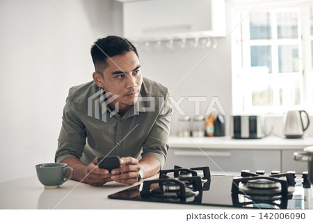 Thinking, kitchen and man online with smartphone for trending updates or popular topics on social media or internet. Person, cellphone and texting for messaging or connection, streaming and download. Thinking, kitchen and man online with smartphone for trending updates or popular topics on social media or internet. Person, cellphone and texting for messaging or connection, streaming and download. 142006090