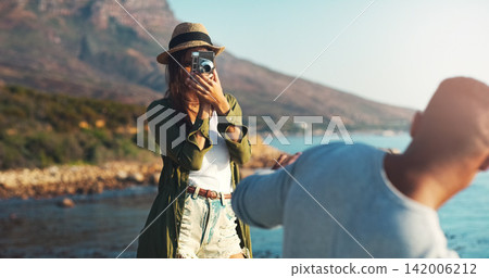 Couple, photography and beach with camera for trip, memory or outdoor moment together in nature. Woman or photographer taking picture of man, boyfriend or partner on adventure by ocean coast Couple, photography and beach with camera for trip, memory or outdoor moment together in nature. Woman or photographer taking picture of man, boyfriend or partner on adventure by ocean coast 142006212