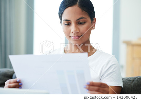 Woman, documents and reading with paperwork for finance, budget planning or expenses on sofa at home. Young female person with smile for daily schedule, pay slip or checking bills on house or assets Woman, documents and reading with paperwork for finance, budget planning or expenses on sofa at home. Young female person with smile for daily schedule, pay slip or checking bills on house or assets 142006425