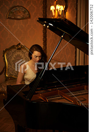Mansion, woman and paying with musician, lounge and pianist in a ballroom with luxury instrument. Entertainment, palace and vintage fashion of sound artist with song and manor with glamour and style 142006752