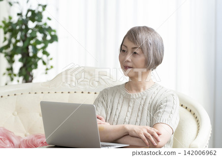 一位老年婦女在客廳使用電腦 一位老年婦女在客廳使用電腦 142006962
