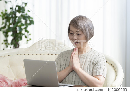 一位老年婦女在客廳使用電腦 142006963