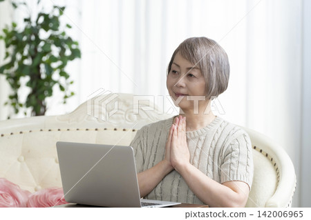 一位老年婦女在客廳使用電腦 142006965