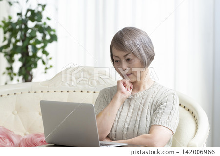 一位老年婦女在客廳使用電腦 一位老年婦女在客廳使用電腦 142006966