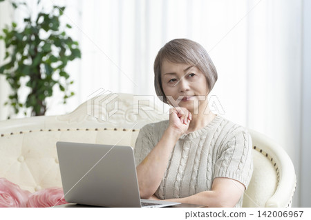 一位老年婦女在客廳使用電腦 一位老年婦女在客廳使用電腦 142006967