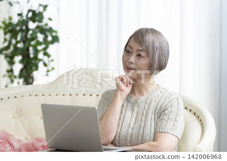 一位老年婦女在客廳使用電腦 一位老年婦女在客廳使用電腦 142006968