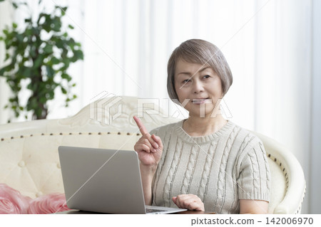一位老年婦女在客廳使用電腦 一位老年婦女在客廳使用電腦 142006970