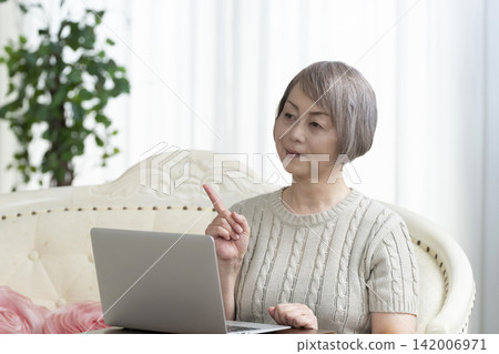 一位老年婦女在客廳使用電腦 一位老年婦女在客廳使用電腦 142006971