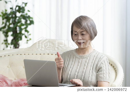 一位老年婦女在客廳使用電腦 一位老年婦女在客廳使用電腦 142006972