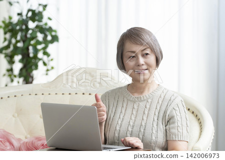 一位老年婦女在客廳使用電腦 142006973