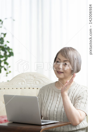 一位老年婦女在客廳使用電腦 142006984