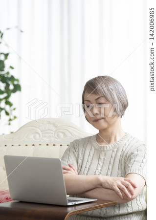 一位老年婦女在客廳使用電腦 一位老年婦女在客廳使用電腦 142006985