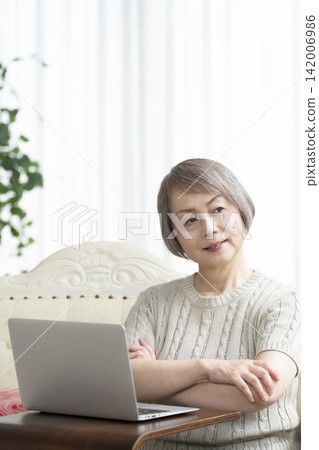 一位老年婦女在客廳使用電腦 一位老年婦女在客廳使用電腦 142006986