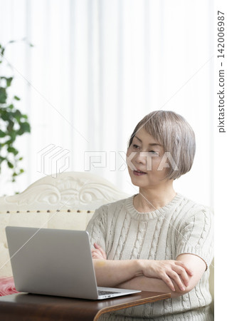 一位老年婦女在客廳使用電腦 一位老年婦女在客廳使用電腦 142006987