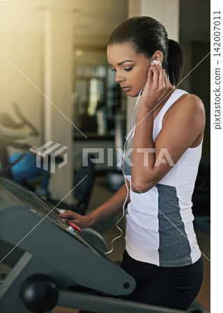Black woman, gym and music in treadmill for workout to exercise and fitness routine for health. Female person, earphone and training or commitment for wellness, wellbeing and self care in sportswear Black woman, gym and music in treadmill for workout to exercise and fitness routine for health. Female person, earphone and training or commitment for wellness, wellbeing and self care in sportswear 142007011