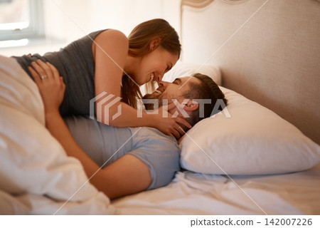 Love, care and happy couple in bed with romance, desire or intimacy, connection or bonding at home. Eye contact, foreplay and passion, attraction or trust in bedroom for anniversary or honeymoon Love, care and happy couple in bed with romance, desire or intimacy, connection or bonding at home. Eye contact, foreplay and passion, attraction or trust in bedroom for anniversary or honeymoon 142007226