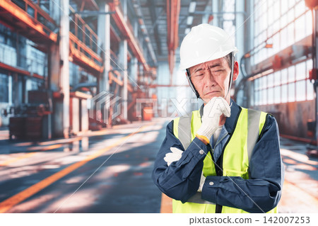 工廠裡,一名男子雙手抱頭。 工廠裡,一名男子雙手抱頭。 142007253