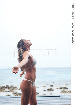 Woman, beach and calm in bikini in nature, arms and relax on seaside holiday, Swimwear, ocean and waves on summer vacation in Hawaii, happy and smile for profile of female person outdoor with freedom Woman, beach and calm in bikini in nature, arms and relax on seaside holiday, Swimwear, ocean and waves on summer vacation in Hawaii, happy and smile for profile of female person outdoor with freedom 142007406