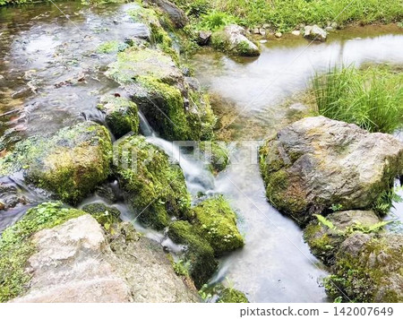 A landscape of a gentle stream flowing over rocky terrain. A landscape of a gentle stream flowing over rocky terrain. 142007649