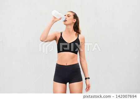 Woman, athlete and drinking water in studio, thirsty and hydrate after workout on white background. Female person, detox and mineral liquid for recovery after exercise, fitness and mockup space Woman, athlete and drinking water in studio, thirsty and hydrate after workout on white background. Female person, detox and mineral liquid for recovery after exercise, fitness and mockup space 142007694