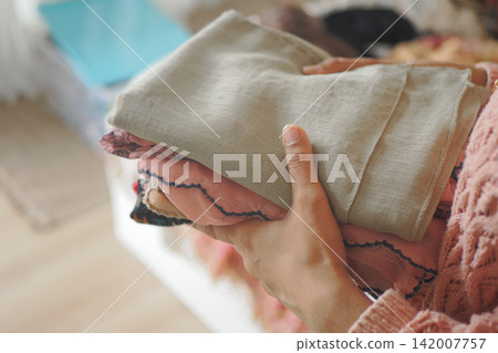 Holding folded clothes in a home setting Holding folded clothes in a home setting 142007757