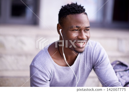 Outdoor, earphones and black man in campus, smile and listening to audio, radio and music in morning. Academy, student and university for person, education and knowledge in Atlanta, city and relax Outdoor, earphones and black man in campus, smile and listening to audio, radio and music in morning. Academy, student and university for person, education and knowledge in Atlanta, city and relax 142007775