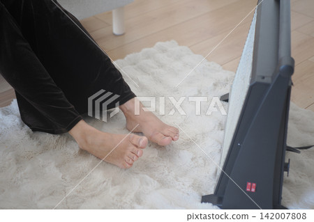 Bare Feet Warming by a Space Heater on a Cozy Rug in a Living Room Bare Feet Warming by a Space Heater on a Cozy Rug in a Living Room 142007808