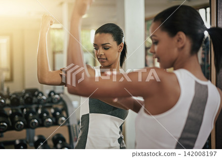 Woman, reflection or flexing in mirror at gym with fitness, workout and exercise of bodybuilder with growth. Progress, strong or confident girl athlete with sport training, wellness or bicep muscle Woman, reflection or flexing in mirror at gym with fitness, workout and exercise of bodybuilder with growth. Progress, strong or confident girl athlete with sport training, wellness or bicep muscle 142008197