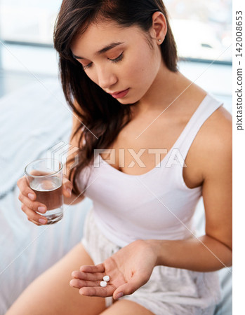 Hand, medicine and water with woman in bedroom of home from above for prescription, supplement or vitamins. Healthcare, medical and pills with young person on bed in apartment for morning medication Hand, medicine and water with woman in bedroom of home from above for prescription, supplement or vitamins. Healthcare, medical and pills with young person on bed in apartment for morning medication 142008653