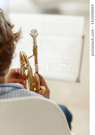 Sheets, music and child with trumpet for learning, jazz lesson and practice for talent show. Musician, creative hobby and excited young boy with instrument, paper and home to play song or melody 142008664