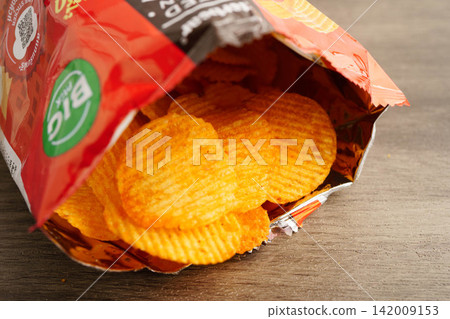 Bangkok, Thailand - May 15, 2022 Potato chips in open bag, delicious BBQ seasoning spicy for crips, thin slice deep fried snack fast food. Bangkok, Thailand - May 15, 2022 Potato chips in open bag, delicious BBQ seasoning spicy for crips, thin slice deep fried snack fast food. 142009153
