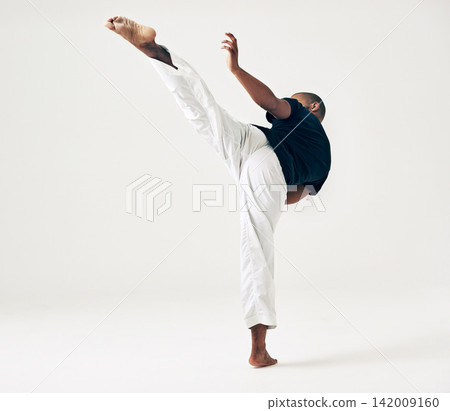 Man, studio and martial arts for kick fight, action and karate exercise on white background. Black male person, mockup space and training for combat, fitness and position of attack in taekwondo Man, studio and martial arts for kick fight, action and karate exercise on white background. Black male person, mockup space and training for combat, fitness and position of attack in taekwondo 142009160