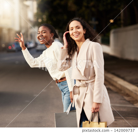 Women, city and calling for taxi after shopping with smile, happiness with sale on product. Female friends, together and hand sign with fashion in urban for car, transport or travel from sidewalk Women, city and calling for taxi after shopping with smile, happiness with sale on product. Female friends, together and hand sign with fashion in urban for car, transport or travel from sidewalk 142009737