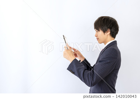 A young businessman operating a tablet against a white background. A young businessman operating a tablet against a white background. 142010043