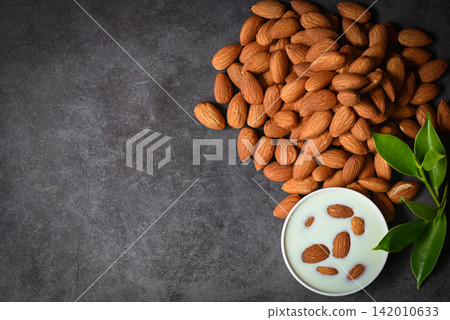 Almond milk and Almonds nuts on dark background, Delicious sweet almonds on table, roasted almond nut for healthy food and snack - top view Almond milk and Almonds nuts on dark background, Delicious sweet almonds on table, roasted almond nut for healthy food and snack - top view 142010633
