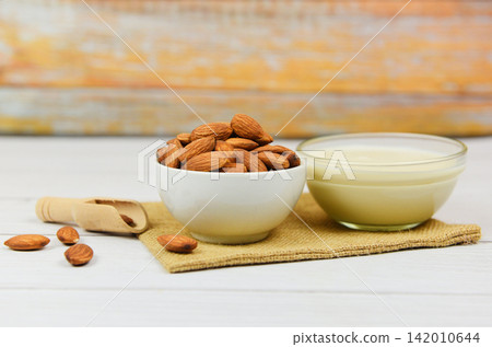 Almond milk in bowl and almonds on wooden scoop on sack Almond milk in bowl and almonds on wooden scoop on sack 142010644