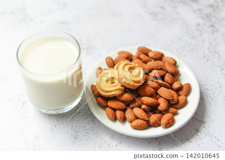 almond milk glass and cookie for breakfast health food - almonds nuts on white plate background almond milk glass and cookie for breakfast health food - almonds nuts on white plate background 142010645