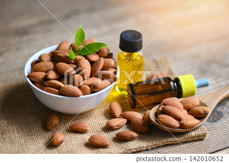 Almond oil and Almonds nuts on bowl, Delicious sweet almonds oil in glass bottle, roasted almond nut for healthy food and snack organic vegetable oils for cooking or spa concept Almond oil and Almonds nuts on bowl, Delicious sweet almonds oil in glass bottle, roasted almond nut for healthy food and snack organic vegetable oils for cooking or spa concept 142010652