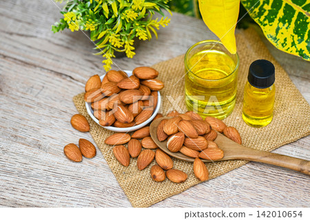 Almond oil and Almonds nuts on table, Delicious sweet almonds oil in glass bottle, roasted almond nut for healthy food and snack organic vegetable oils for cooking or spa Almond oil and Almonds nuts on table, Delicious sweet almonds oil in glass bottle, roasted almond nut for healthy food and snack organic vegetable oils for cooking or spa 142010654