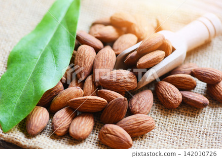 Almonds on wooden scoop and sack  background top view on the table, Close up roasted almond nuts natural protein food and for snack 142010726