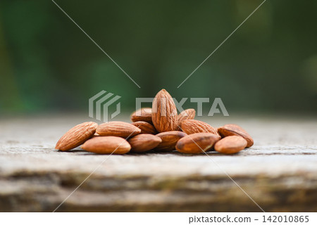 Almonds on wooden table and nature background / Close up almond nuts natural protein food and for snack Almonds on wooden table and nature background / Close up almond nuts natural protein food and for snack 142010865