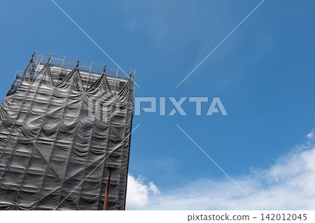 Scaffolding and black mesh sheeting at an apartment building under repair. Scaffolding and black mesh sheeting at an apartment building under repair. 142012045