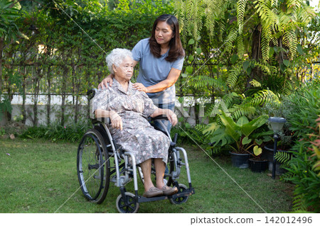 Caregiver help Asian elderly woman disability patient sitting on wheelchair in park, medical concept. Caregiver help Asian elderly woman disability patient sitting on wheelchair in park, medical concept. 142012496