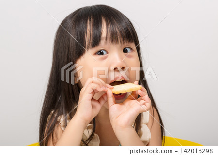 Cute little Asian girl eating a crispy cracker with mouth wide open, hungry child snacking Cute little Asian girl eating a crispy cracker with mouth wide open, hungry child snacking 142013298
