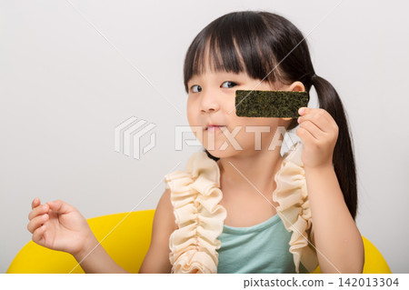 Happy Asian kid holding a piece of seaweed snack, healthy dried seaweed concept for children. Happy Asian kid holding a piece of seaweed snack, healthy dried seaweed concept for children. 142013304