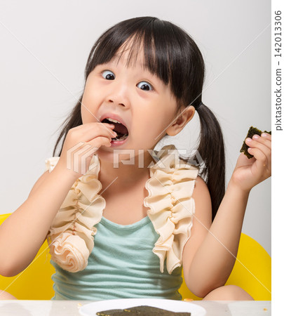 Happy Asian kid holding a piece of seaweed snack, healthy dried seaweed concept for children. Happy Asian kid holding a piece of seaweed snack, healthy dried seaweed concept for children. 142013306