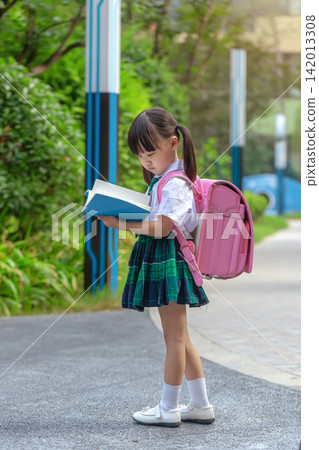 Curious school girl reading a book while walking to class, thirst for knowledge concept. Curious school girl reading a book while walking to class, thirst for knowledge concept. 142013308