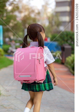 Rear view of a little girl with a pink backpack walking to school, new semester and educational growth. Rear view of a little girl with a pink backpack walking to school, new semester and educational growth. 142013309